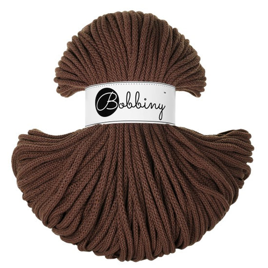 A skein of Bobbiny braided cord in a rich dark brown color, featuring a white paper label with the brand name 'Bobbiny' in black script, set against a plain white background.
