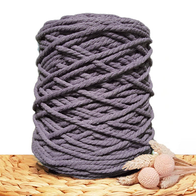 A large roll of 5mm twisted cord in a muted dark grey blue color, styled on a woven straw mat with dried decorative grasses against a white background.