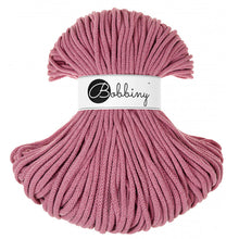 A skein of blossom pink braided rope  with a white paper label in the center that reads 'Bobbiny' in black script and logo, set against a plain white background.