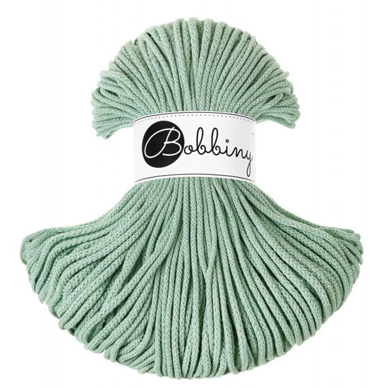 A skein of soft green braided cord with a white paper label in the center featuring the brand name 'Bobbiny' in black script.