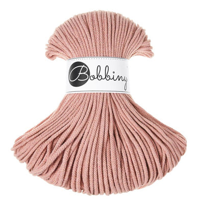 A skein of dusty pink braided cord, wrapped with a white paper band featuring the brand name 'Bobbiny' in black script and logo, set against a plain white background.