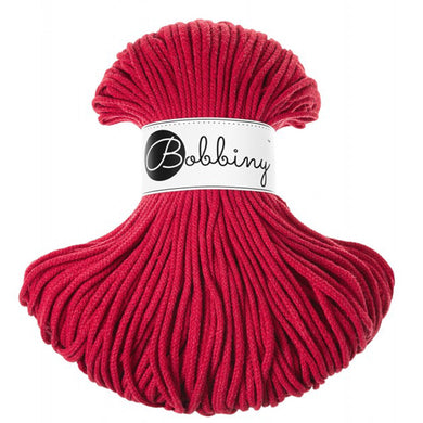 A skein of bright red bobbiny braided cord with a white paper label that reads 'Bobbiny' in black script, set against a plain white background.