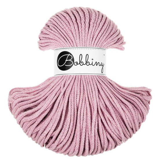 A skein of dusty pink braided cord with a white paper label in the center that reads 'Bobbiny' in black script and logo, set against a plain white background.