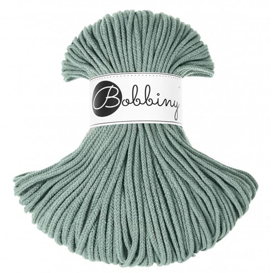 A skein of laurel green braided cord with a white paper label in the center that reads 'Bobbiny'.