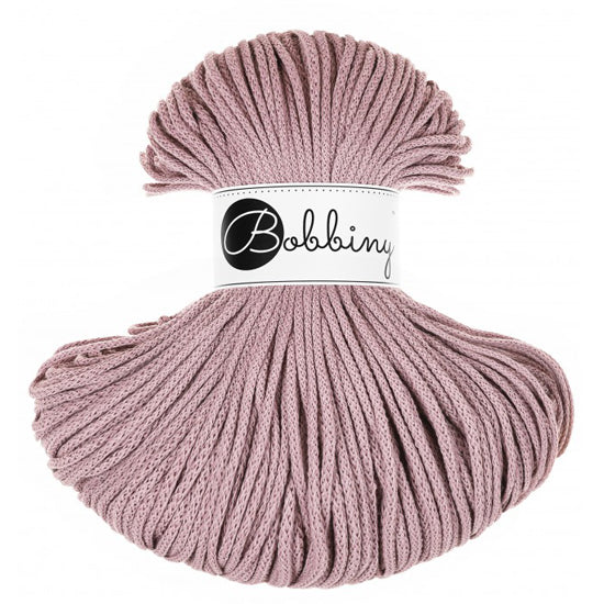 A skein of mauve braided cord with a white paper label in the center that reads 'Bobbiny' in black script and logo, set against a plain white background.