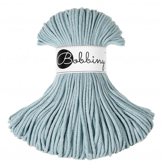 A skein of Bobbiny brand light blue braided cord with a white paper label, shown against a plain white background.
