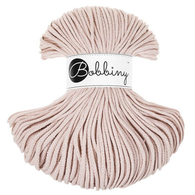 A skein of Bobbiny braided cord in a soft pink or nude shade featuring a white paper label with the brand name 'Bobbiny' in black script. The yarn is arranged in a rounded, fan-like shape against a solid white background.