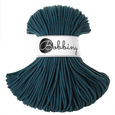 A skein of dark teal braided cord with a white paper label that reads 'Bobbiny' in black script, set against a plain white background.