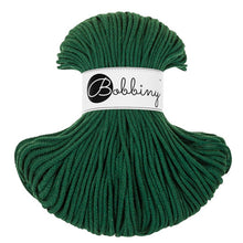 A skein of dark green braided cord with a white paper label in the center that reads 'Bobbiny' in black script and logo, set against a plain white background.