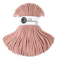 A skein of blush braided cord with a white paper band in the center featuring the black script logo 'Bobbiny'.