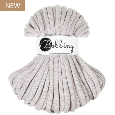 A skein of light grey braided cord with a white paper label wrapped around the middle that reads 'Bobbiny'. A small tan 'NEW' badge is in the top-left corner.