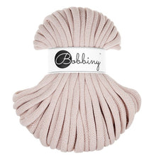 A skein of nude chunky braided cord with a white paper label wrapped around it, featuring the brand name 'Bobbiny' in black script and logo, set against a plain white background.
