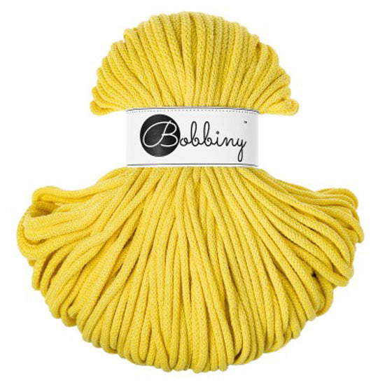 A skein of canary yellow cord with a white paper label wrapped around the center, featuring the brand name 'Bobbiny' in black script.