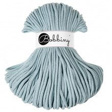 A skein of light blue braided cord with a white paper label wrapped around the middle that reads 'Bobbiny'.