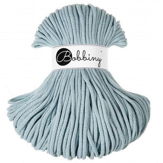 A skein of light blue braided cord with a white paper label wrapped around the middle that reads 'Bobbiny'.