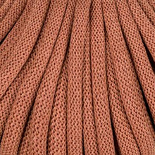 A close-up of braided cord in a warm rust-brown terracotta color, shown with vertical folds filling the frame.