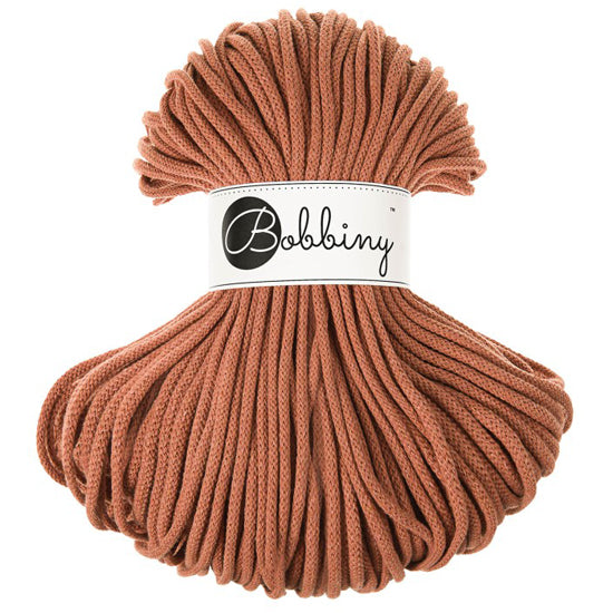 A skein of terracotta brown braided cord with a white paper label in the center that reads 'Bobbiny'.